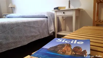 a book sitting on a table next to a bed at Villa Lindi in Castellammare del Golfo