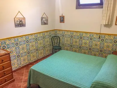 a bedroom with a green bed and a chair at VILLA VENERE con vista sul mare in San Vito lo Capo
