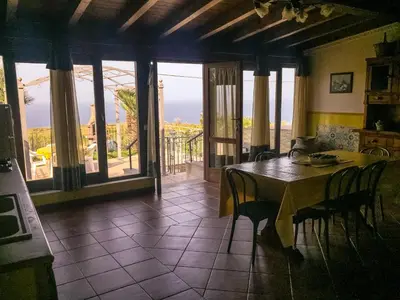 a dining room with a table and chairs and a balcony at VILLA VENERE con vista sul mare in San Vito lo Capo