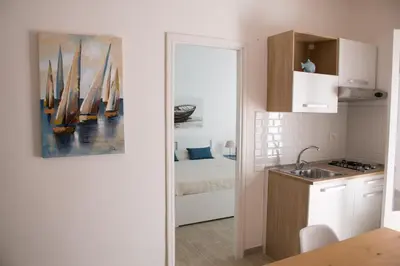 a kitchen with a view of a bedroom with a bed at Casa Vacanze Mondello Mare Piscina ALBAMAOR in Mondello