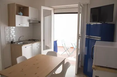 a kitchen with a table and a blue refrigerator at Casa Vacanze Mondello Mare Piscina ALBAMAOR in Mondello