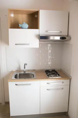 a white kitchen with a sink and a stove at Casa Vacanze Mondello Mare Piscina ALBAMAOR in Mondello