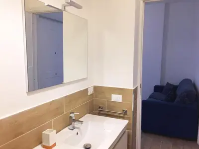 a bathroom with a sink and a mirror and a blue couch at Casa Vacanze Mondello Mare Piscina ALBAMAOR in Mondello
