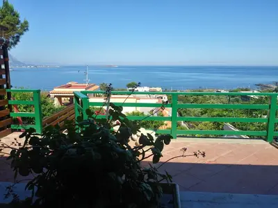 a green fence with a view of the ocean at tramonto blu in Palermo