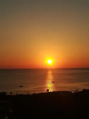 a sunset over the ocean with boats in the water at tramonto blu in Palermo