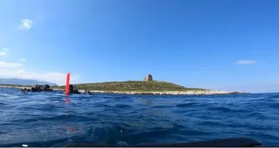 a small island in the water with a lighthouse on it at Bed Ponente in Isola delle Femmine