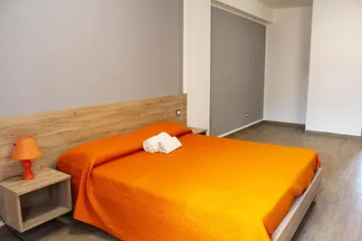 a bedroom with an orange bed and a lamp at Bed Ponente in Isola delle Femmine