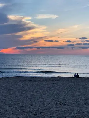 two people sitting on the beach at sunset at Bed Ponente in Isola delle Femmine