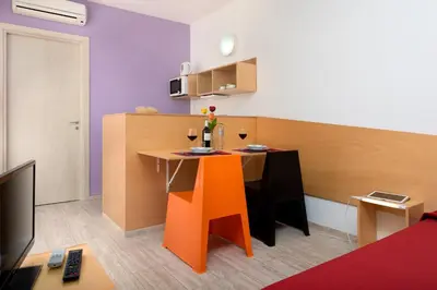 a small kitchen with a table and orange chairs at Vitorno Residence in San Vito lo Capo
