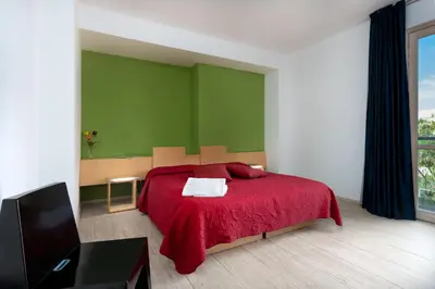 a bedroom with a red bed and a green wall at Vitorno Residence in San Vito lo Capo