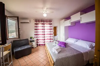 a bedroom with a purple bed and a chair at 'A Cumerdia - Casa Vacanze in Castellammare del Golfo