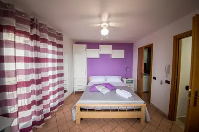 a bedroom with a bed with a purple wall at 'A Cumerdia - Casa Vacanze in Castellammare del Golfo