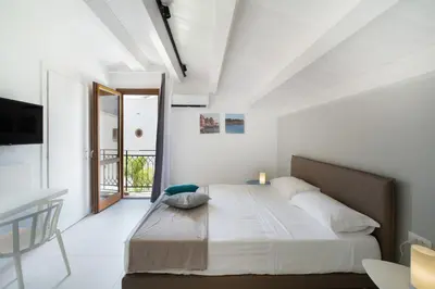 a white bedroom with a large bed and a table at Baglio La Riserva in Scopello