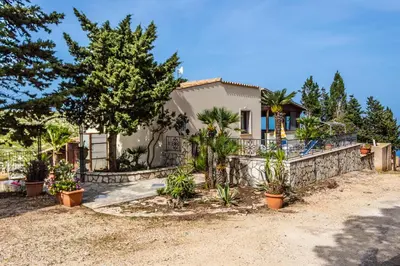 a house with trees and plants in front of it at Villa Verde con vista sul mare in San Vito lo Capo