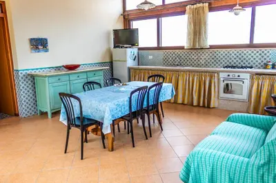 a kitchen with a table and chairs in a room at Villa Verde con vista sul mare in San Vito lo Capo