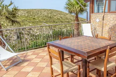 a wooden table and chairs on a balcony with a view at Villa Azzurra con vista sul mare in San Vito lo Capo