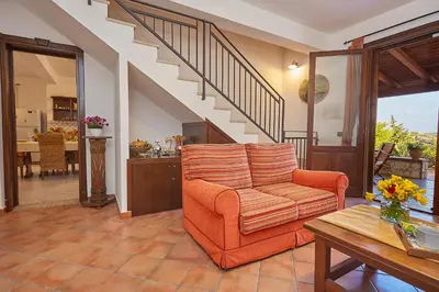 a living room with an orange chair and a table at Villa Sansone in Altavilla Milicia