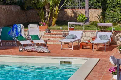 a group of chairs sitting next to a swimming pool at Villa Sansone in Altavilla Milicia