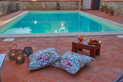 a swimming pool with pillows and a table next to it at Villa Sansone in Altavilla Milicia