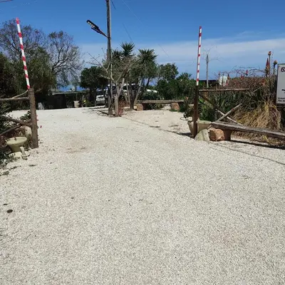 an empty road with a fence and palm trees at Baglio cracchiolo da tuzzo Villa Ulivo in San Vito lo Capo
