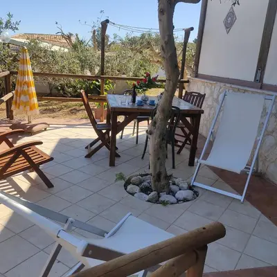 a table and chairs and a tree on a patio at Baglio cracchiolo da tuzzo Villa Ulivo in San Vito lo Capo