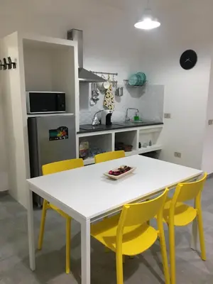 a kitchen with a white table and yellow chairs at Casa Nicuzza in Palermo
