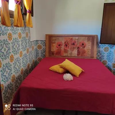 a bed with red sheets and yellow pillows at Casa Fico D'India in San Vito lo Capo
