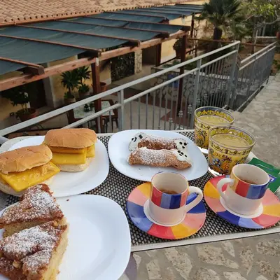 a table with plates of food and cups of coffee at Casa Fico D'India in San Vito lo Capo