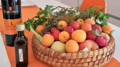a basket of fruit on a table with a bottle of wine at GIULIA E CHIARA LUXURY APARTMENT in Castellammare del Golfo