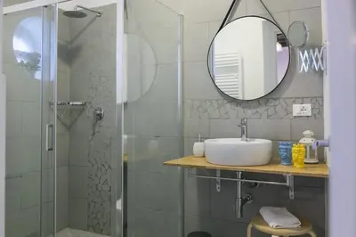 a bathroom with a shower and a sink and a mirror at Corte del Merlo in Palermo