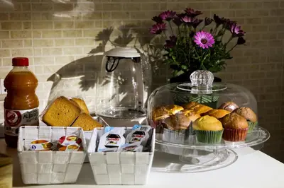 a table with muffins and cupcakes and a vase with flowers at A Casa di Fra' in Palermo