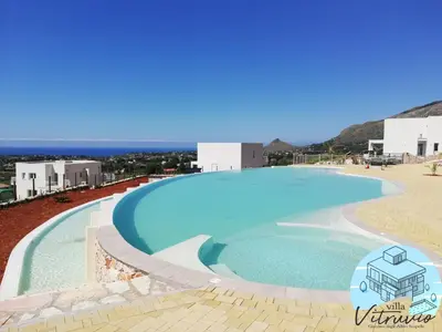 a large swimming pool with a beach and buildings at Villa Vitruvio - Giardino degli Allori Scopello in Castellammare del Golfo