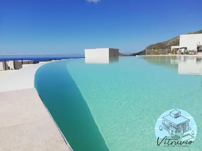 a pool on the beach with the water at Villa Vitruvio - Giardino degli Allori Scopello in Castellammare del Golfo