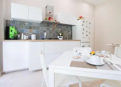 a kitchen with white cabinets and a white table and chairs at Le Stanze Dell'Emiro in Palermo