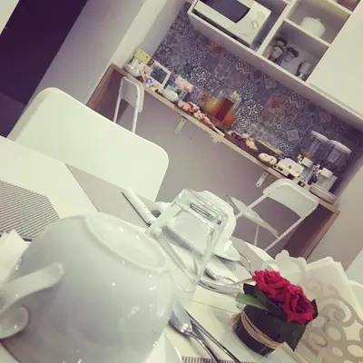 a kitchen table with white dishes and a rose on it at Le Stanze Dell'Emiro in Palermo