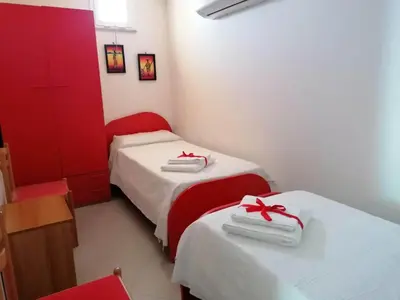 two beds in a room with red cabinets at APPARTAMENTO L'AIRONE in Balestrate