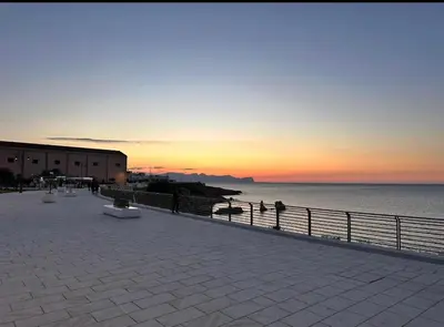 a sunset over the ocean with a fence and the beach at CASA CALISI in Terrasini
