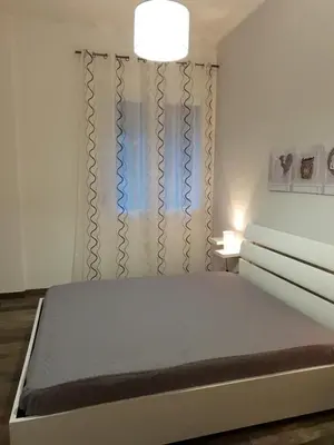 a white bedroom with a bed and a lamp at CASE VACANZE NONNA NICK in Castellammare del Golfo