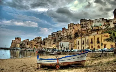 a boat sitting on the beach in front of a city at CASE VACANZE NONNA NICK in Castellammare del Golfo