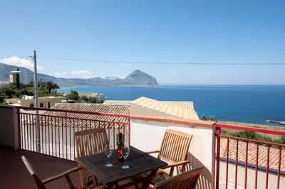 a table on a balcony with a view of the ocean at Villa Gina con vista mozzafiato sul golfo di Macari in Macari