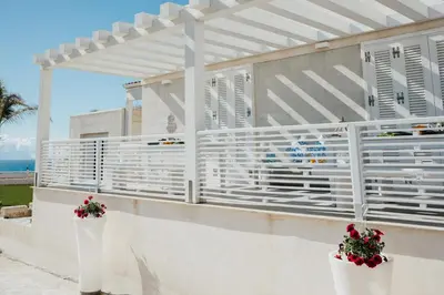 a white pergola on the side of a building at Giardini del Golfo Villa al Mare in Balestrate