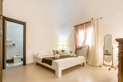 a white bedroom with a bed and a mirror at Casa marty in Mondello