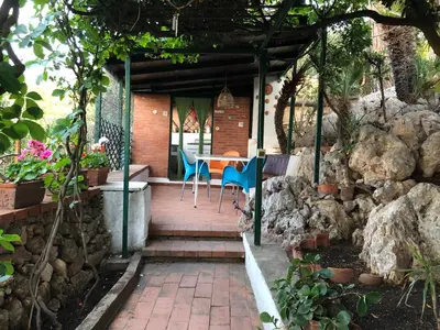 a patio with a table and chairs and a stone wall at Casa Elvira in Terrasini