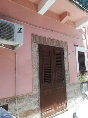 a pink house with a brown door and a fan at Terra e Mare in Capaci