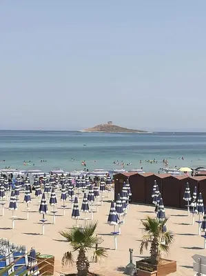 a beach with chairs and umbrellas and people in the ocean at Terra e Mare in Capaci