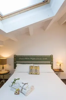 a bedroom with a white bed with a green headboard at Addimora Boutique Suites in Palermo