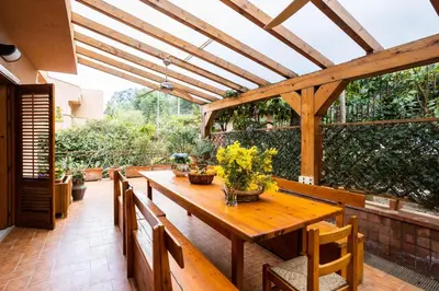 a wooden table and chairs on a patio at Villa nel verde sul mare, Mondello, Palermo in Palermo