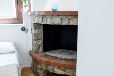 a stone fireplace in a room with a bed at Zangara Flat in Cinisi
