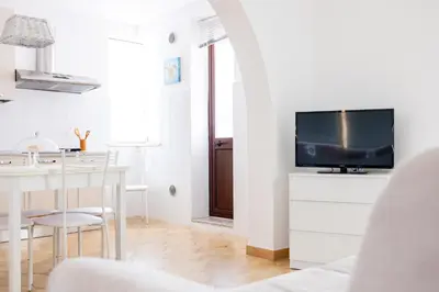 a white living room with a tv and a table at Zangara Flat in Cinisi