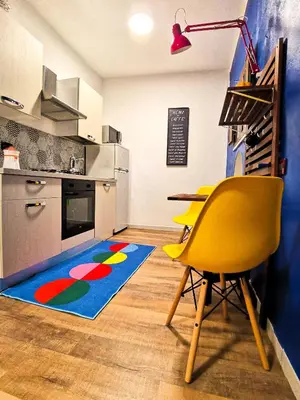 a kitchen with a table and a yellow chair and a rug at CasuzzaMia in Palermo